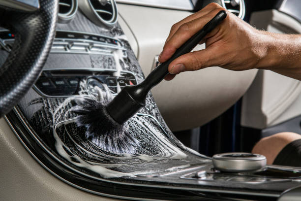 Detailing brush scrubbing foam into a car center console during an interior deep clean in Springfield, MO